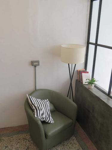 a green chair with a pillow in a room with windows at 墾丁包棟民宿哪尼 - 2位即可包棟 in Eluan