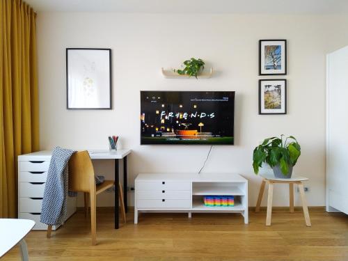 uma sala de estar com uma secretária e uma televisão na parede em SUNSET Apartment Near Sea - family friendly space with bath and good coffee em Ventspils