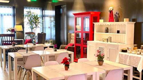 um restaurante com mesas e cadeiras brancas e um armário vermelho em Arc My Otel em Ponte de Lima
