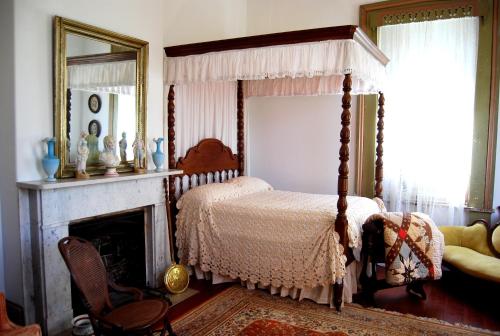 a bedroom with a canopy bed and a fireplace at Glenfield Plantation Historic Antebellum Bed and Breakfast in Natchez