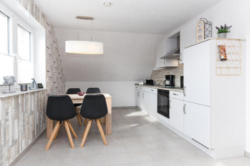 een witte keuken met zwarte stoelen en een tafel bij Ferienwohnung im Haus Hafenlicht in Neuharlingersiel