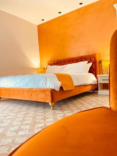 a bedroom with a bed with an orange wall at Casa Reale Boutique Hotel in Valletta