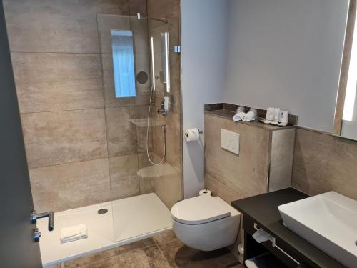 a bathroom with a shower and a toilet and a sink at Best Western Plus Parkhotel Maximilian Ottobeuren in Ottobeuren
