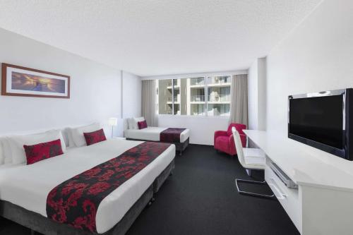 a hotel room with two beds and a television at Ramada By Wyndham Marcoola Beach in Marcoola