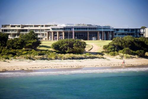 a building on the beach next to the ocean at Wyndham Resort Torquay in Torquay