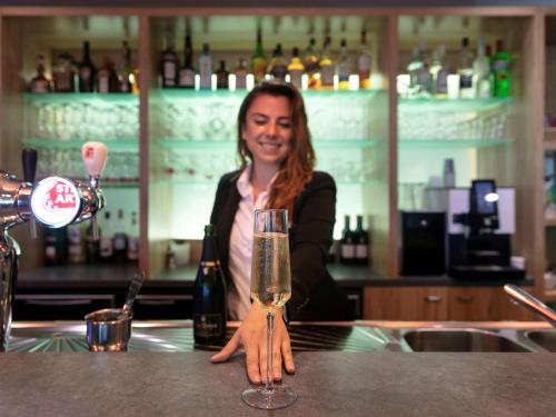 a woman sitting at a bar with a glass of wine at ibis Styles Zeebrugge in Zeebrugge