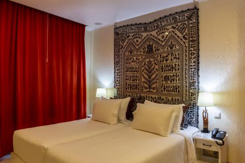 a hotel room with a bed and a red curtain at Hotel A.S. Lisboa in Lisbon