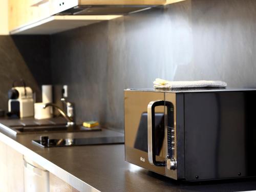 un four micro-ondes installé au-dessus d'un comptoir de cuisine dans l'établissement Trankil'Apparts Gare, à Saint-Quentin