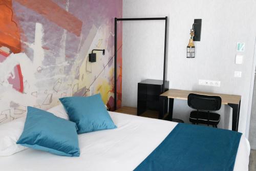 um quarto com uma cama com almofadas azuis e uma secretária em The Originals Boutique, Hôtel Montélimar em Montélimar
