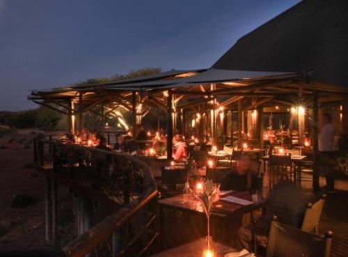 un restaurante con gente sentada en las mesas por la noche en Buffelsdrift Game Lodge, en Oudtshoorn