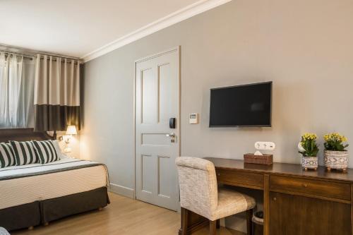 a bedroom with a bed and a desk with a television at Aenos Hotel in Argostoli