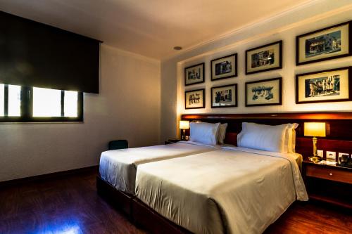 a bedroom with a large bed and framed pictures on the wall at Hotel A.S. Lisboa in Lisbon
