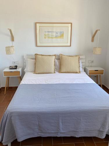a large white bed in a room with two tables at La Terraza de la Sabina in Es Mercadal