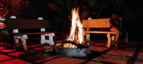 a man sitting on a bench next to a fire at Chirooss resort in Chikmagalūr