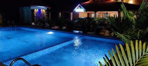 a swimming pool at night with a house in the background at Chirooss resort in Chikmagalūr