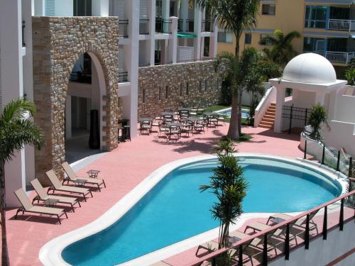 a swimming pool with chaise lounges and chairs near a building at The Sebel Whitsundays in Airlie Beach