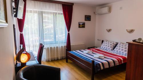 een kleine slaapkamer met een bed en een raam bij Apartmani "Vila Jelena" Arandjelovac in Arandjelovac