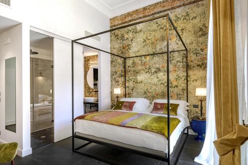 1 dormitorio con cama con dosel y mural en la pared en Relais Antica Badia - San Maurizio 1619, en Ragusa