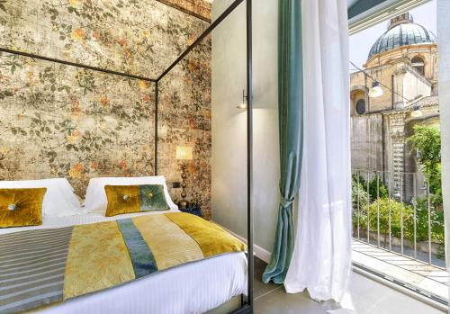 a bedroom with a bed and a large window at Relais Antica Badia - San Maurizio 1619 in Ragusa