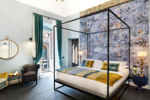 a bedroom with a canopy bed with a floral wallpaper at Relais Antica Badia - San Maurizio 1619 in Ragusa