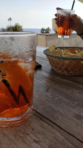 a glass of iced tea on a wooden table with a bowl at Alabe Hotel Marina di Tresnuraghes in Tresnuraghes
