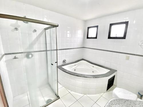 a white bathroom with a tub and a shower at Hotel Canada in Ribeirão Preto