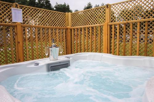 a hot tub in a backyard with a wooden fence at Hollicarrs - Long Lane Lodge in York