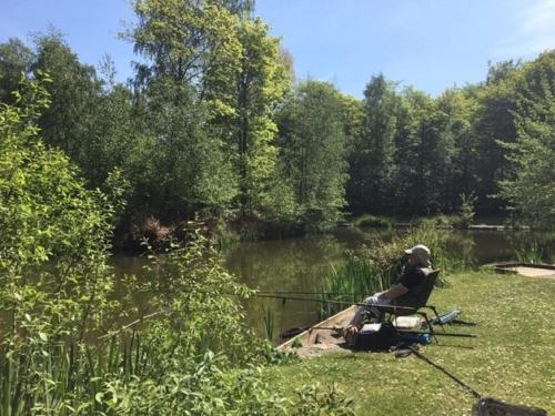 a man sitting in a chair fishing in a pond at Hollicarrs - Long Lane Lodge in York