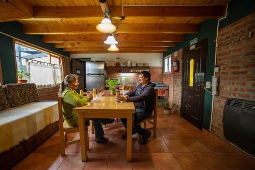 a man and woman sitting at a table in a kitchen at Complejo Turistico Bambu in El Bolsón