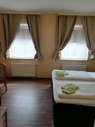 two beds in a room with two windows at Pension Kuehnauer Hof in Dessau