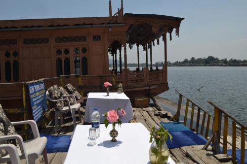 a table and chairs on a boat on the water at Houseboats Jackson Heights in Srinagar
