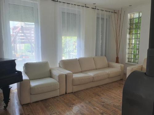 a living room with two white couches and a piano at Ivett apartmanház in Balatonlelle