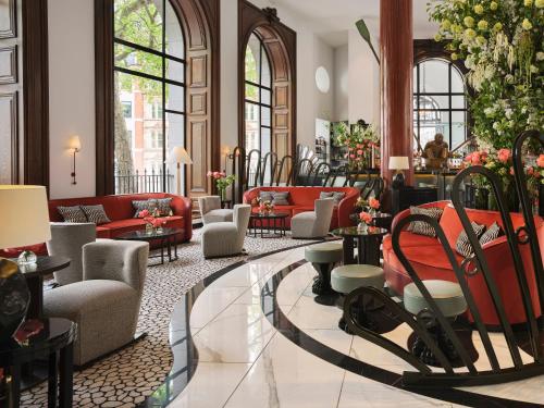 a lobby with couches and chairs and tables and windows at One Aldwych in London