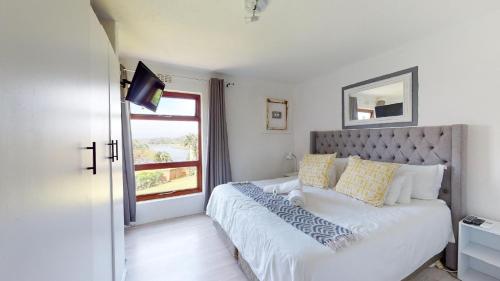 ein Schlafzimmer mit einem großen Bett mit Fenster in der Unterkunft San Lameer Villa 2008 by Top Destinations Rentals in Southbroom