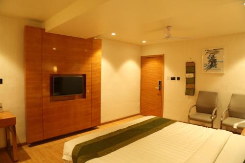 a bedroom with a bed and a flat screen tv at Hotel Reva Regency in Bhopal