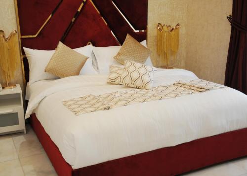 1 cama grande con sábanas y almohadas blancas en Al Nabarees Al Masi Hotel, en Yeda