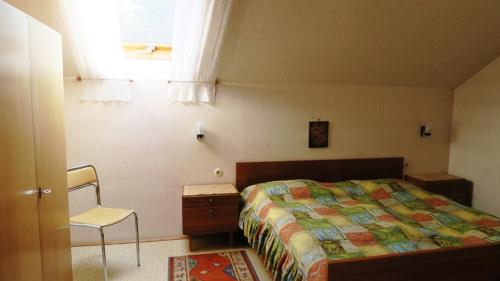 ein Schlafzimmer mit einem Bett und einem Stuhl und einem Fenster in der Unterkunft Ferienwohnung Leitner in Kiefersfelden