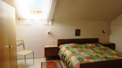 a bedroom with a bed and a chair and a window at Ferienwohnung Leitner in Kiefersfelden