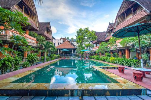 a swimming pool in the courtyard of a building at Troppo Zone Puri Rama Resort Kuta in Legian