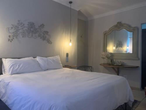 Un dormitorio con una cama blanca y un espejo. en Douglas Villas, en Tzaneen