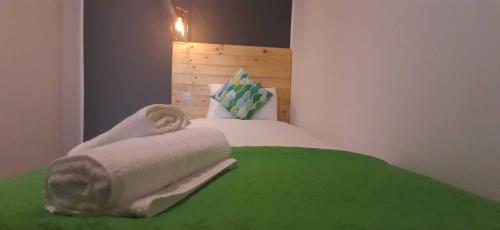 uma cama com um cobertor verde e toalhas em CARO Boutique Guest House em San Ġwann