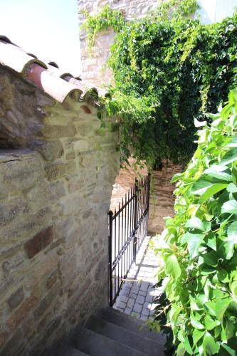 a stairway with a gate on a brick wall at La Maison des Vendangeurs - TABLE D'HÔTES le soir du jeudi au dimanche- Jacuzzi - Balnéo SPA - ACCES PISCINE pour toutes les chambres sauf STUDIO COQUET- Piscine de mai à mi-octobre in Martignargues