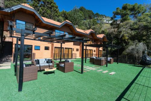 ein Haus mit einem großen Garten mit einer Terrasse in der Unterkunft DOM Hotel Boutique in Campos do Jordão