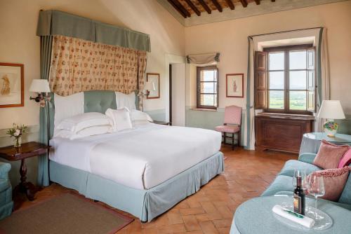 a bedroom with a large white bed and a couch at Castello Banfi - Il Borgo - Relais et Chateaux in Montalcino