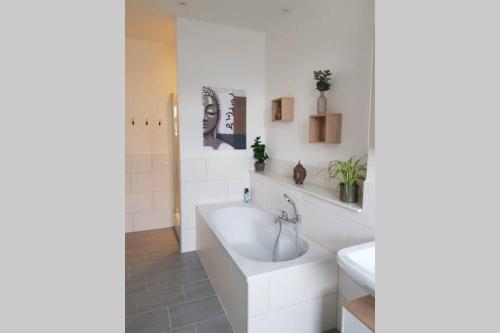 een witte badkamer met een bad en een wastafel bij Ferienwohnung im alten Waschhaus in Spremberg