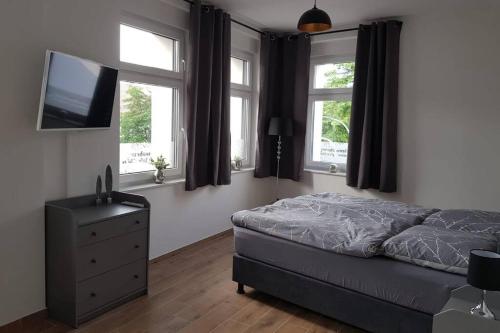 a bedroom with a bed and a tv and windows at Ferienwohnung im alten Waschhaus in Spremberg