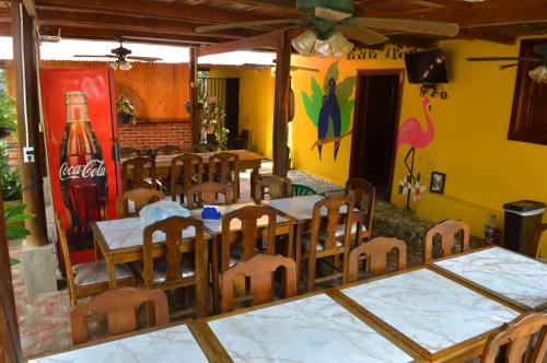 a restaurant with tables and chairs and a coke bottle at EcoHostal Palmares Del Rio in Guachaca