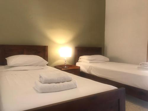 duas camas com lençóis brancos e um candeeiro sobre uma mesa em Sea view Apartments Portobello em St. Paul's Bay