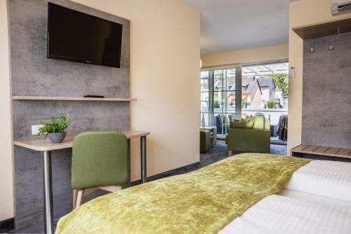 a hotel room with a bed and a flat screen tv at Rheinhotel Rüdesheim - Wellness in Rüdesheim am Rhein