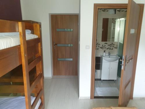 a bedroom with a bunk bed and a bathroom with a sink at Ośrodek Agroturystyka "u Chlipały" in Ochotnica Górna